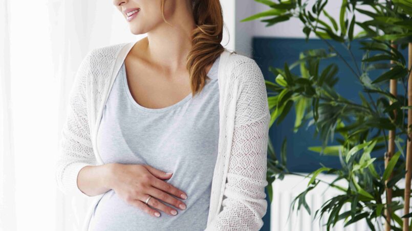 حمل کی علامات جاننے کے بعد ایک عورت مسکراتے ہوئے